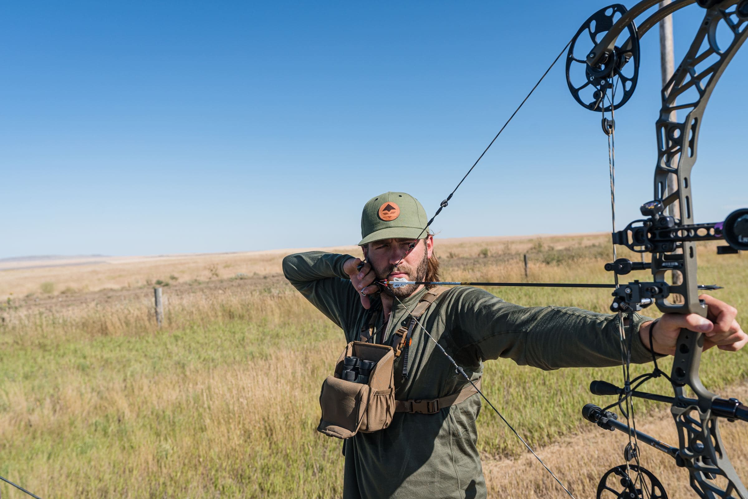Bowhunter at full draw on open prairie