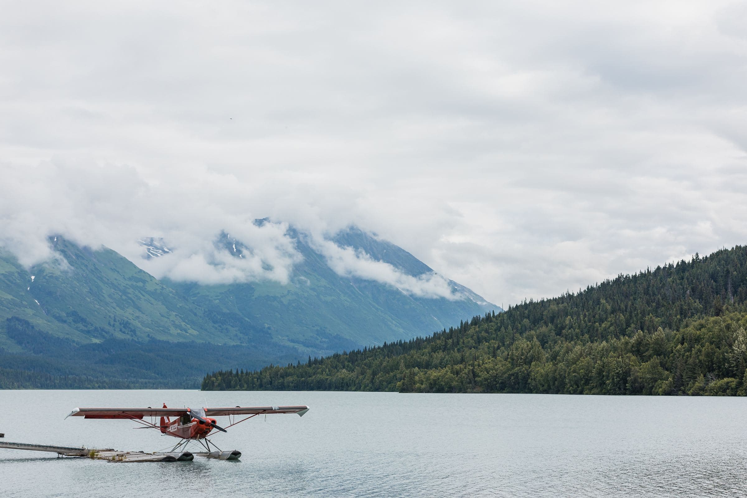 Floatplane on a calm mountain lake beneath low clouds